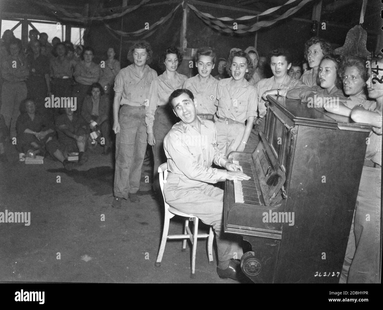 Irving Berlin, famoso scrittore di canzoni di Broadway in tour nella zona sud-occidentale del Pacifico, suona una delle sue canzoni nella sala Women's Army Corps Mess presso la sede centrale delle forze armate statunitensi far East, Hollandia, Dutch New Guinea, 12/24/1944. (Foto di US Army Signal Corps/RBM Vintage Images) Foto Stock