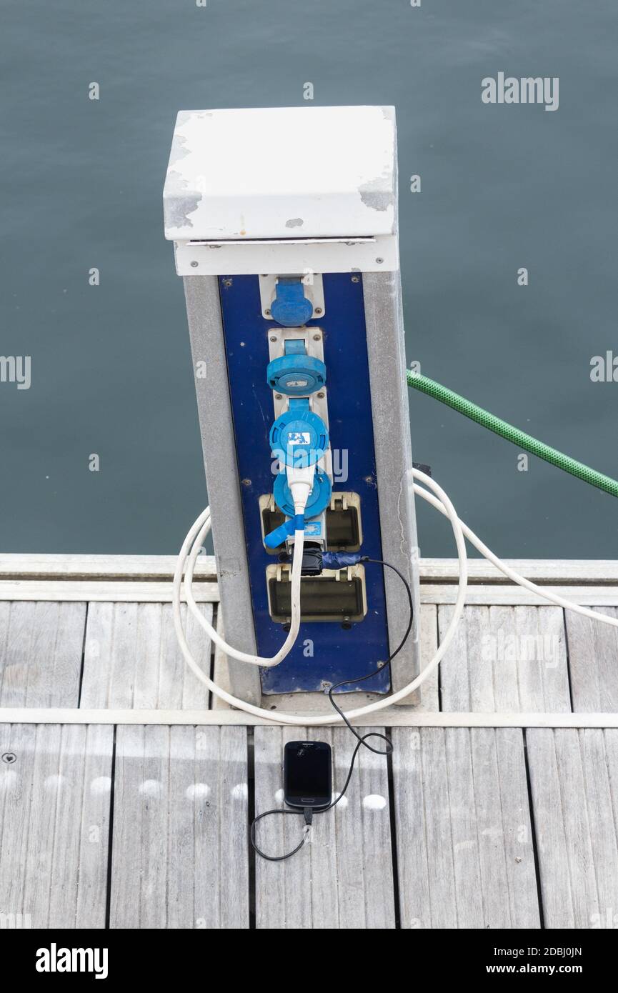 Telefono cellulare/cellulare in carica accanto allo yacht sul porto turistico. Foto Stock