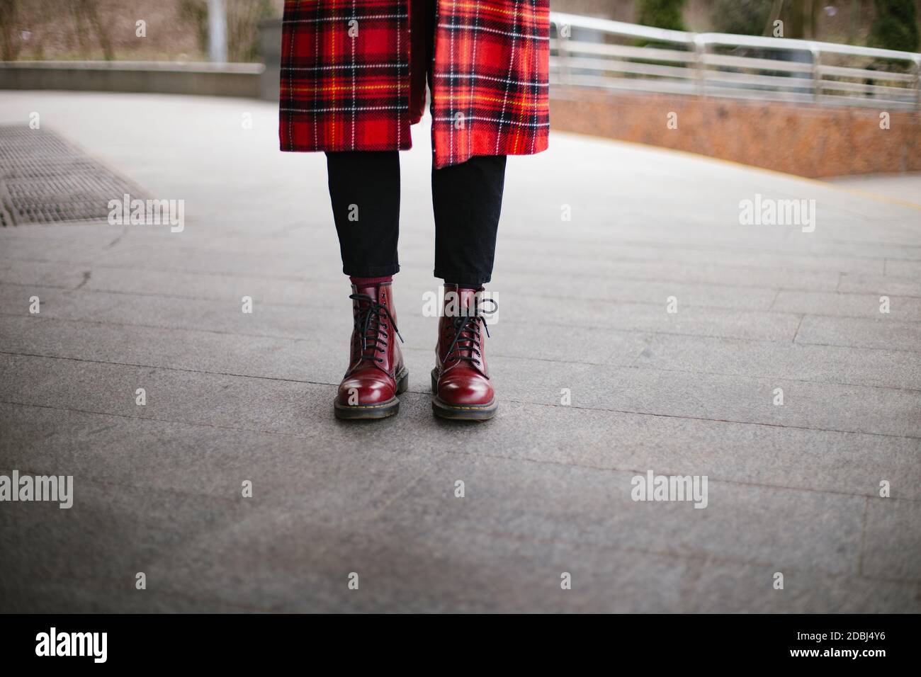 Hipster indossa stivali rossi alla moda e cappotto trench sfondo grigio Foto Stock