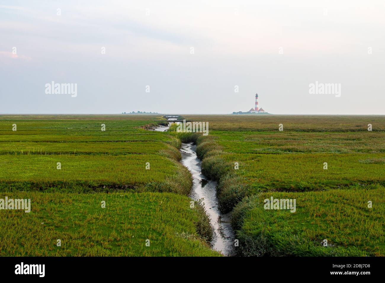 Priel con ponti e faro Westerheversand sullo sfondo Foto Stock