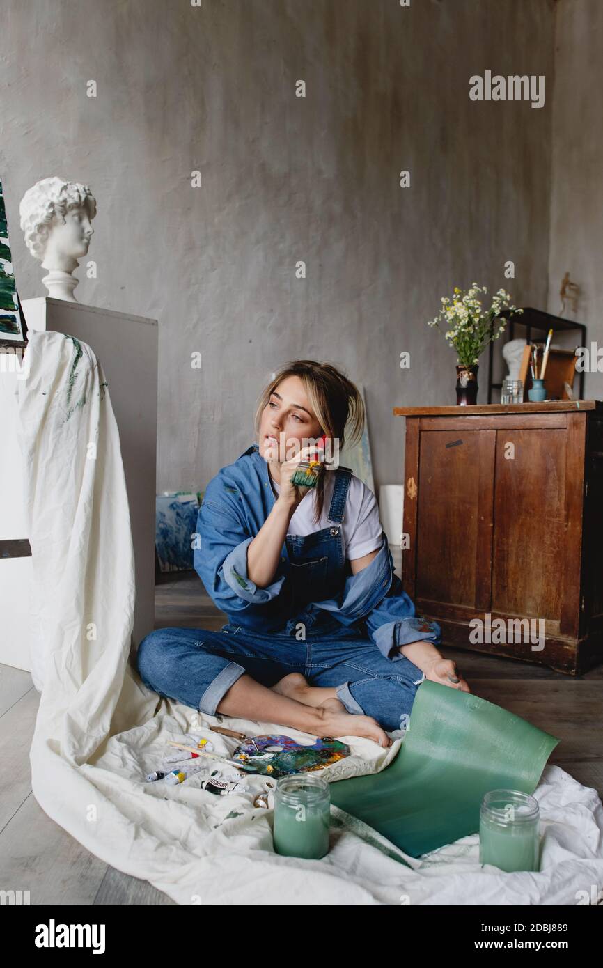 Attraente artista donna bionda che lavora nel suo studio. Foto Stock