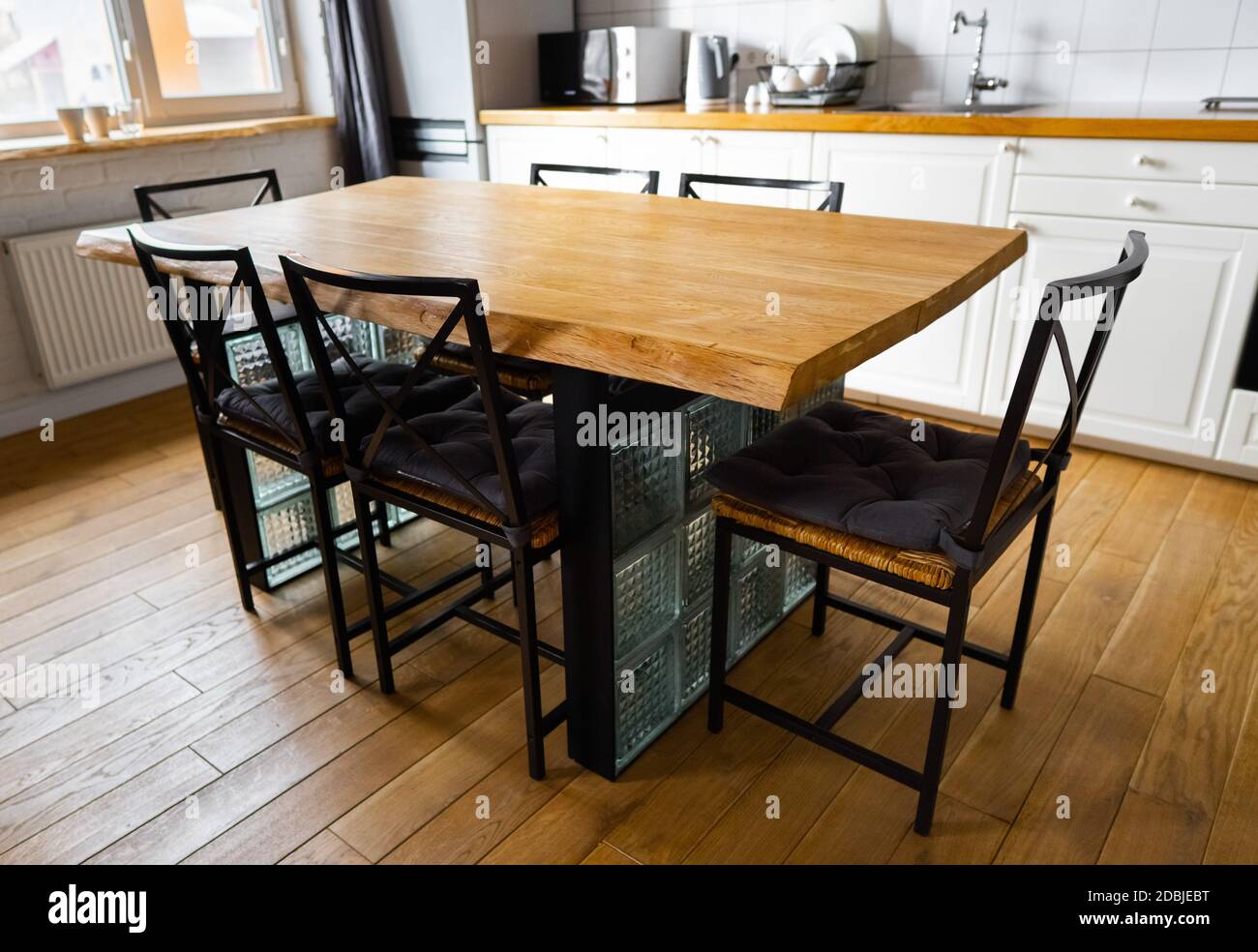 Un grande tavolo da pranzo in legno con blocchi di vetro e sedie e cuscini  in