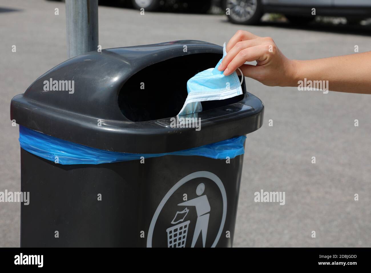 Rispetto dell'ambiente. Gettare la maschera chirurgica in una bidone di rifiuti pubblici in via cittadina. Maschera igienica per la spazzatura. Foto Stock