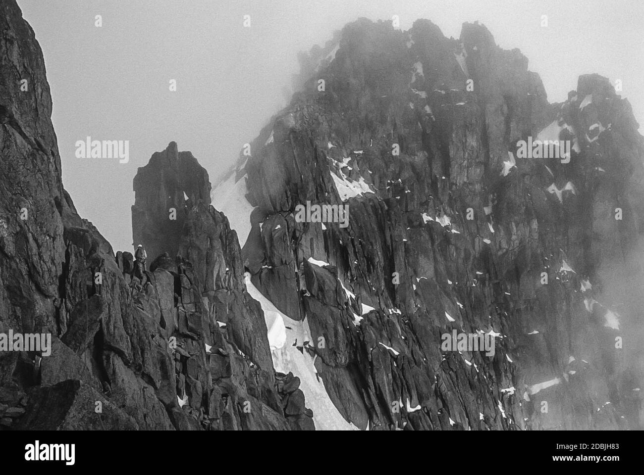 Kenya. Questo è l'alpinismo sul Monte Kenya la montagna più alta del Kenya come è stato nel 1976/77 mostrato qui che attraversa il Gates of Mists tra le cime gemelle di Batian 17.058ft; 5199m a sinistra e Nelion 17.022ft; 5188m nella nuvola a destra. Oltre il gap del Gates of Mists è la testa del Couloir Diamante. Foto Stock