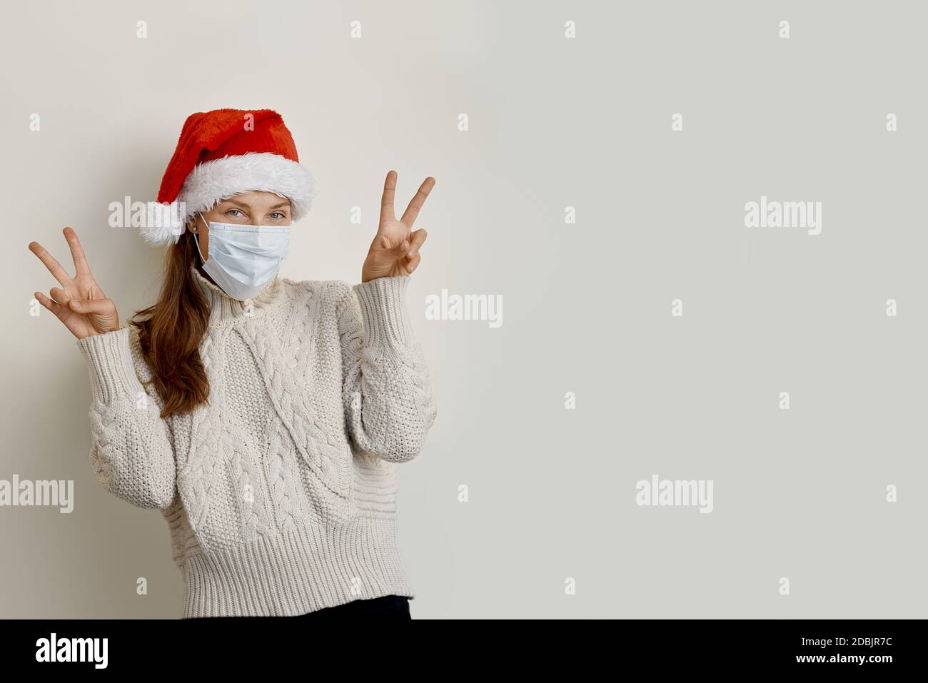 Donna che indossa cappello santa e maschera di protezione facendo segno di vittoria Foto Stock