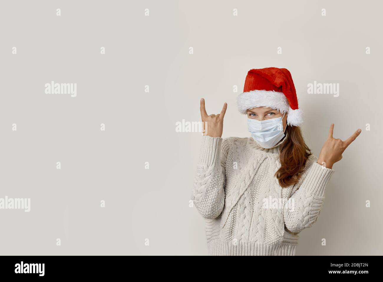 Donna che indossa il cappello di santa facendo simbolo della roccia con le mani in su Foto Stock