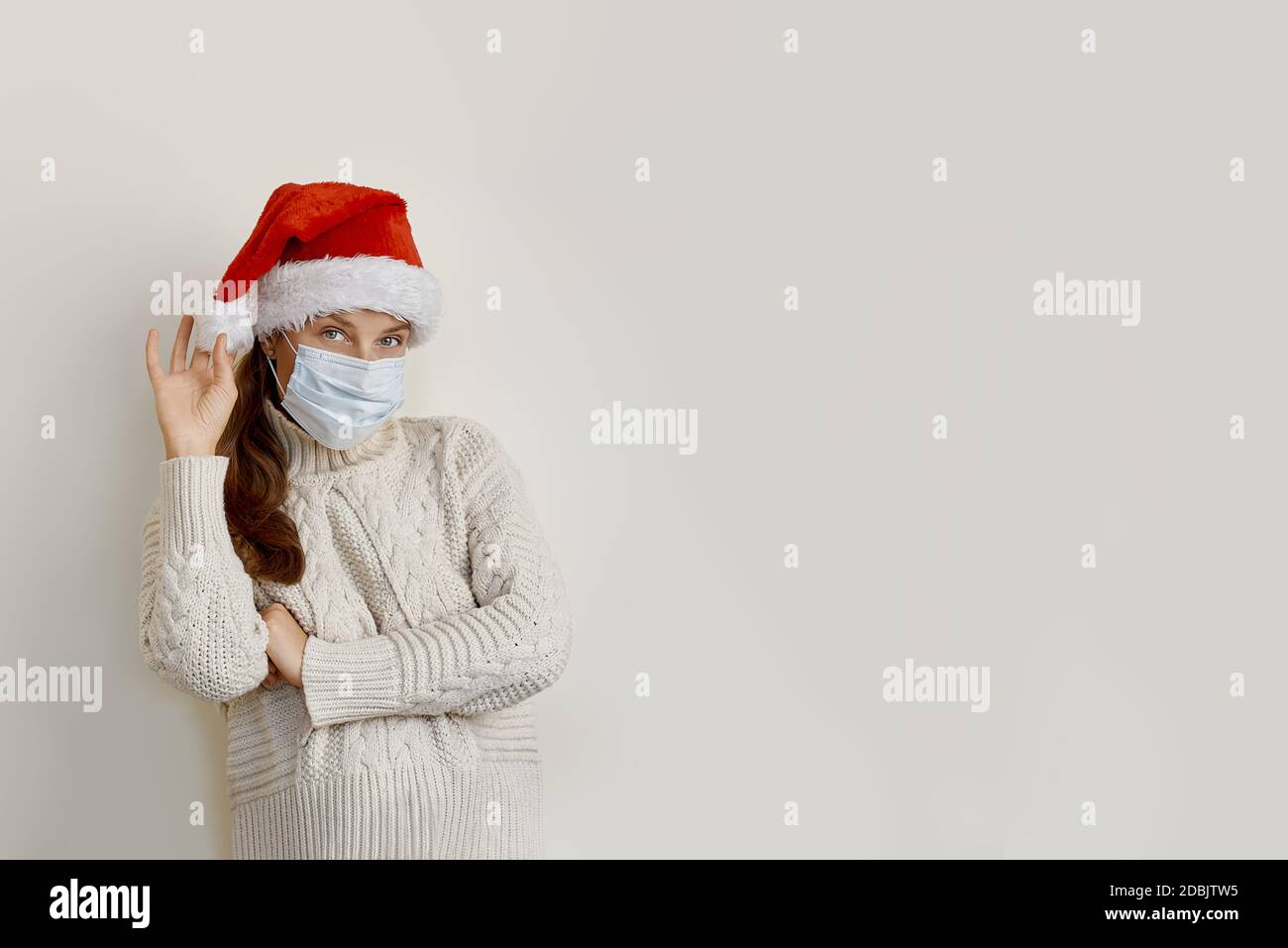 Donna che indossa maschera e cappello di santa in piedi su beige isolato sfondo Foto Stock