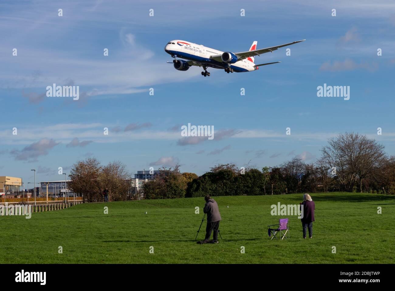 Gli appassionati di aerei, appassionati di aviazione, nel parco spaziale verde vicino a Myrtle Avenue guardando un aereo di linea jet atterrando all'aeroporto di Londra Heathrow, Regno Unito Foto Stock