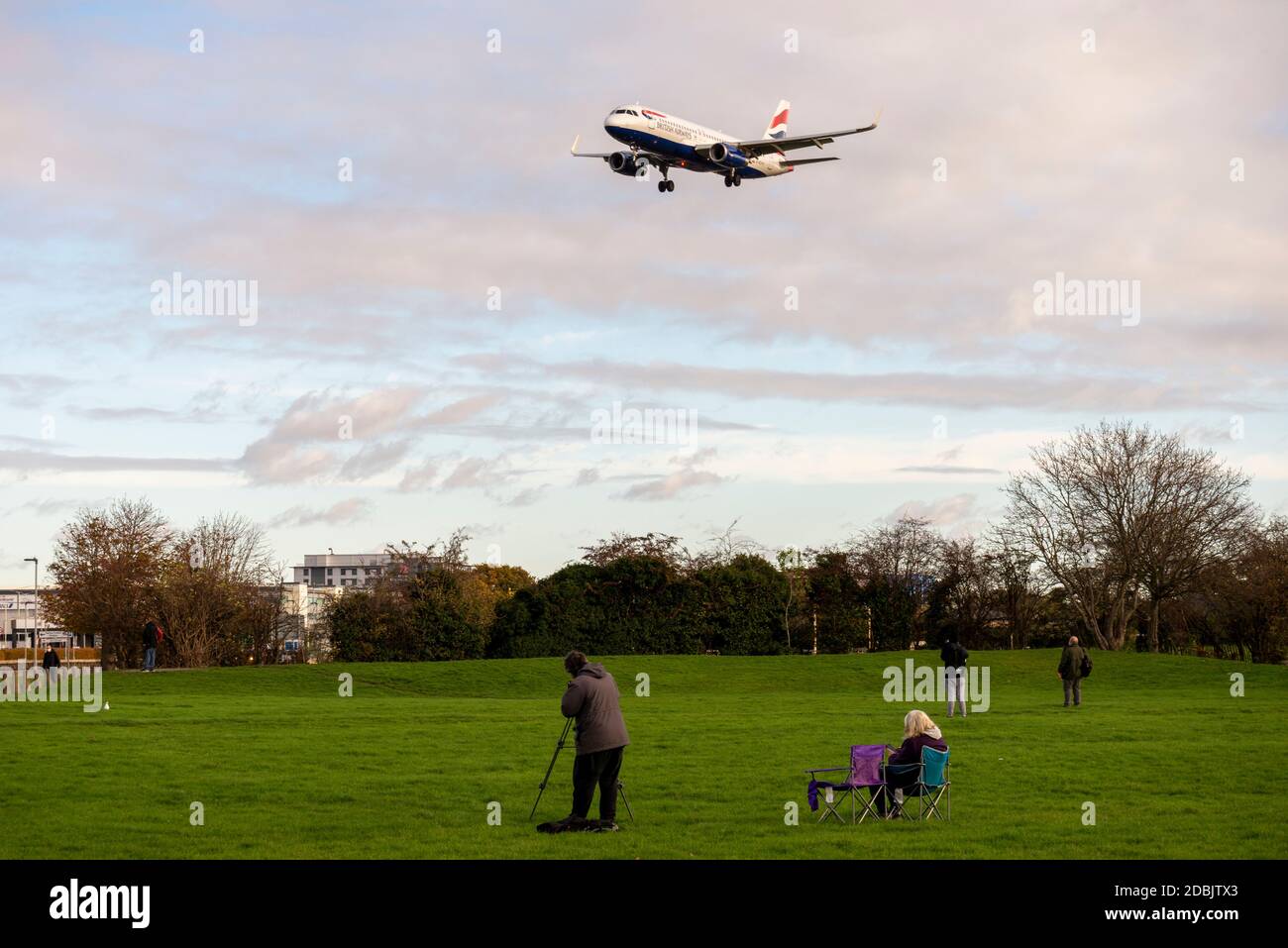 Gli appassionati di aerei, appassionati di aviazione, nel parco spaziale verde vicino a Myrtle Avenue guardando un aereo di linea jet atterrando all'aeroporto di Londra Heathrow, Regno Unito Foto Stock