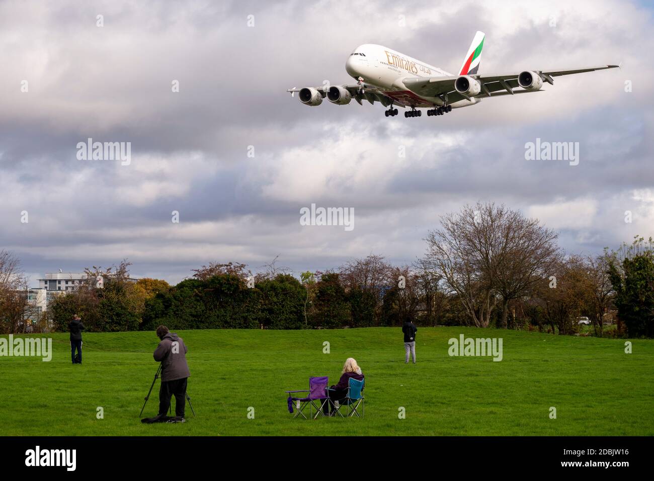 Gli appassionati di aerei, appassionati di aviazione, nel parco spaziale verde vicino a Myrtle Avenue guardando un aereo di linea jet atterrando all'aeroporto di Londra Heathrow, Regno Unito Foto Stock