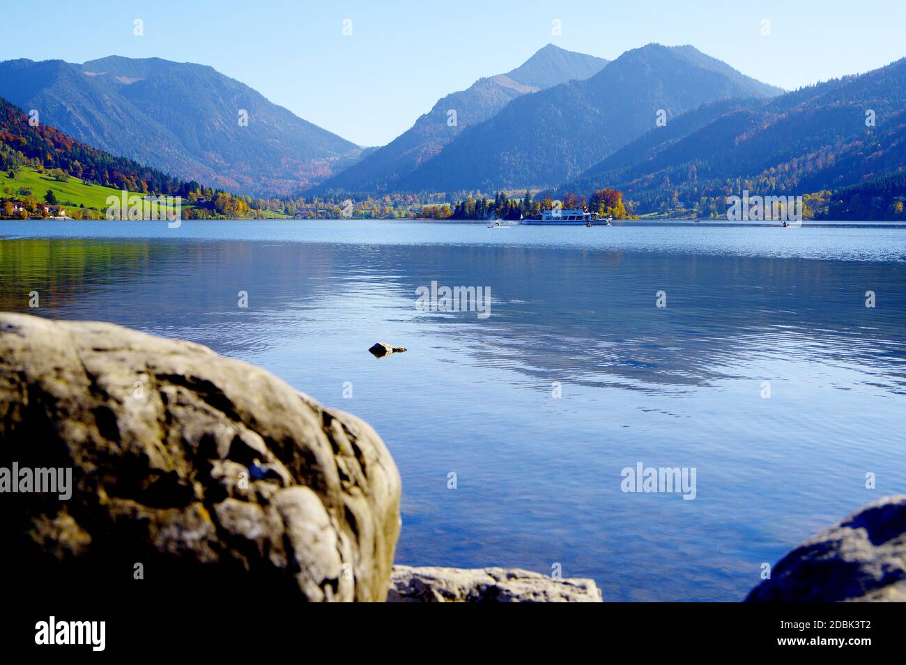 Idilliaco lago di montagna con una barca escursione incorniciata da alte montagne Foto Stock
