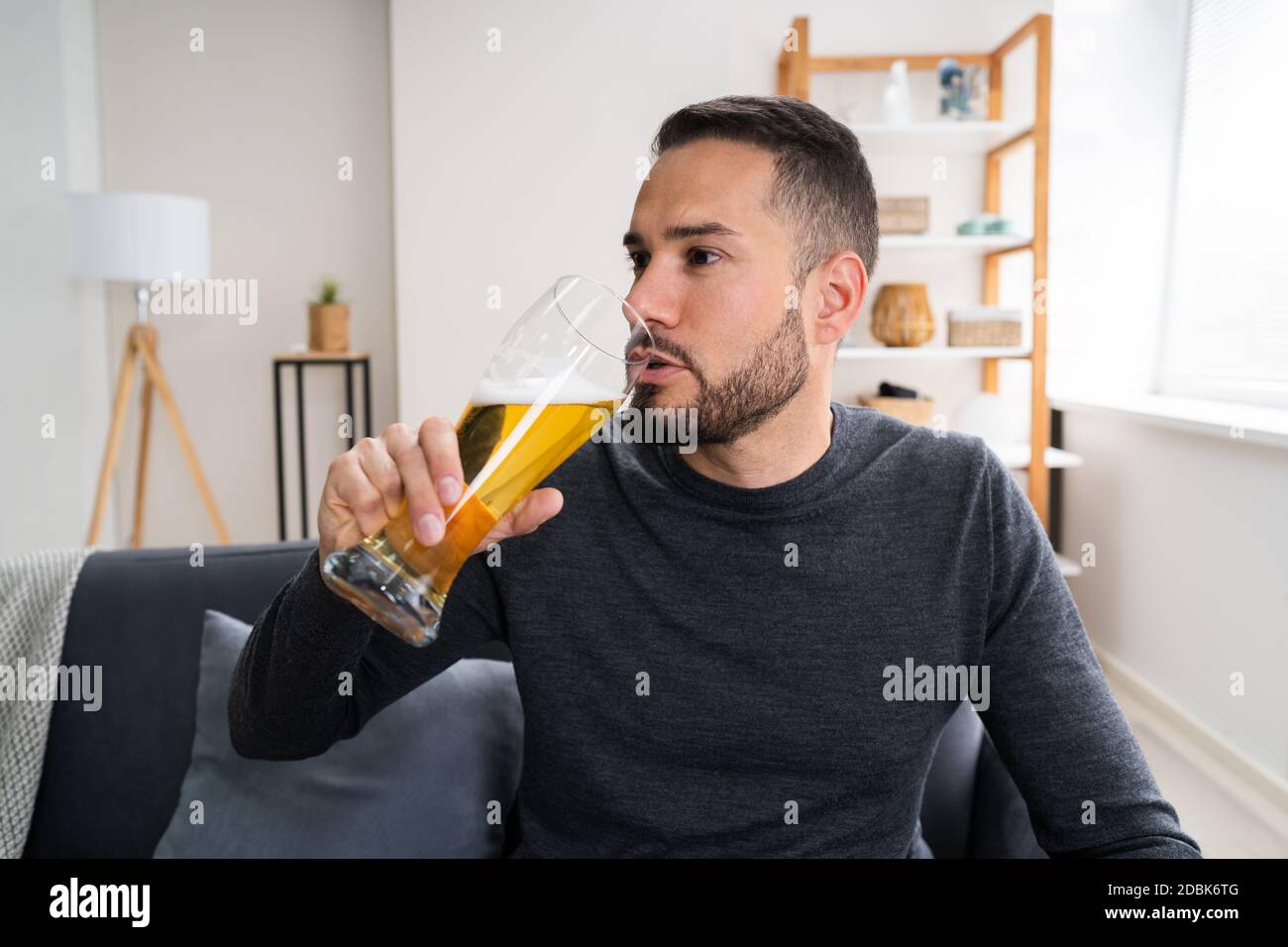 Uomo bere birra da solo a casa Foto Stock