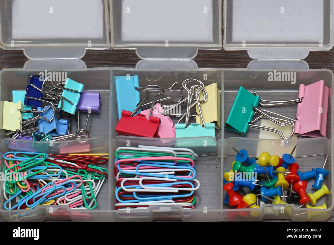La cancelleria colorata fornisce clip di carta e perni in scatola di plastica Foto Stock