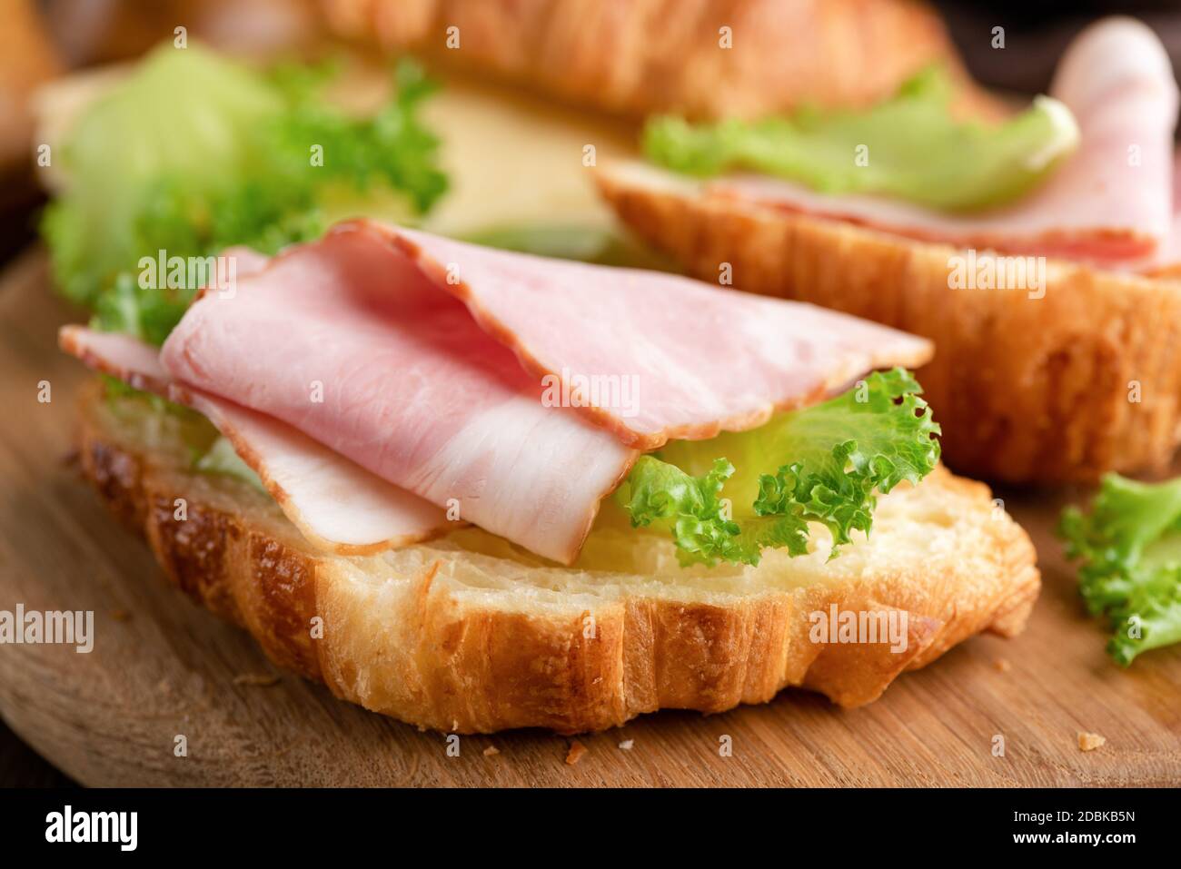 Croissant con prosciutto e formaggio su sfondo di legno, vista guardaroba Foto Stock