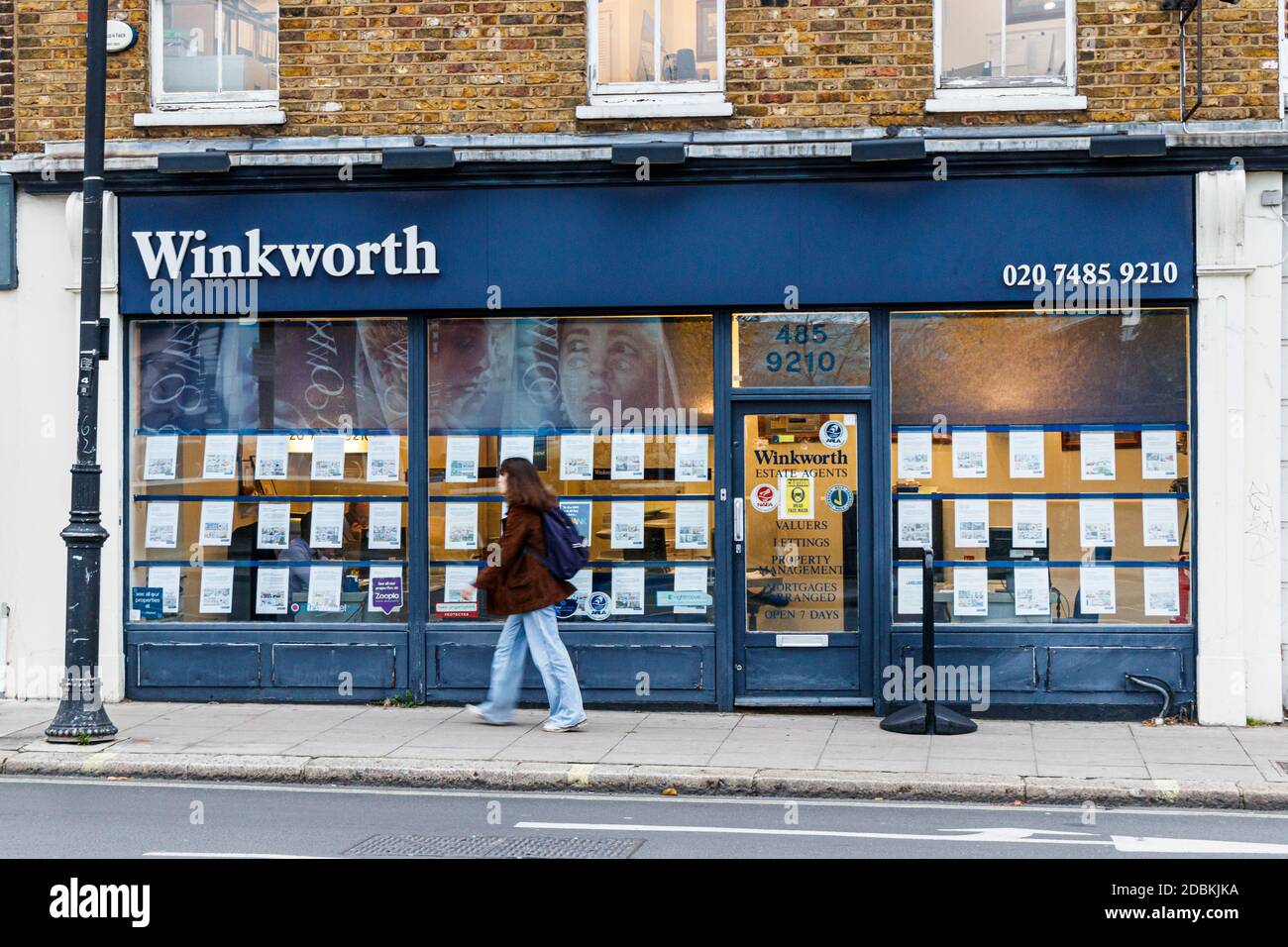 Una donna passa accanto a un ramo dell'agente immobiliare Winkworth, chiuso durante il secondo blocco pandemico coronavirus, Kentish Town, Londra, Regno Unito Foto Stock