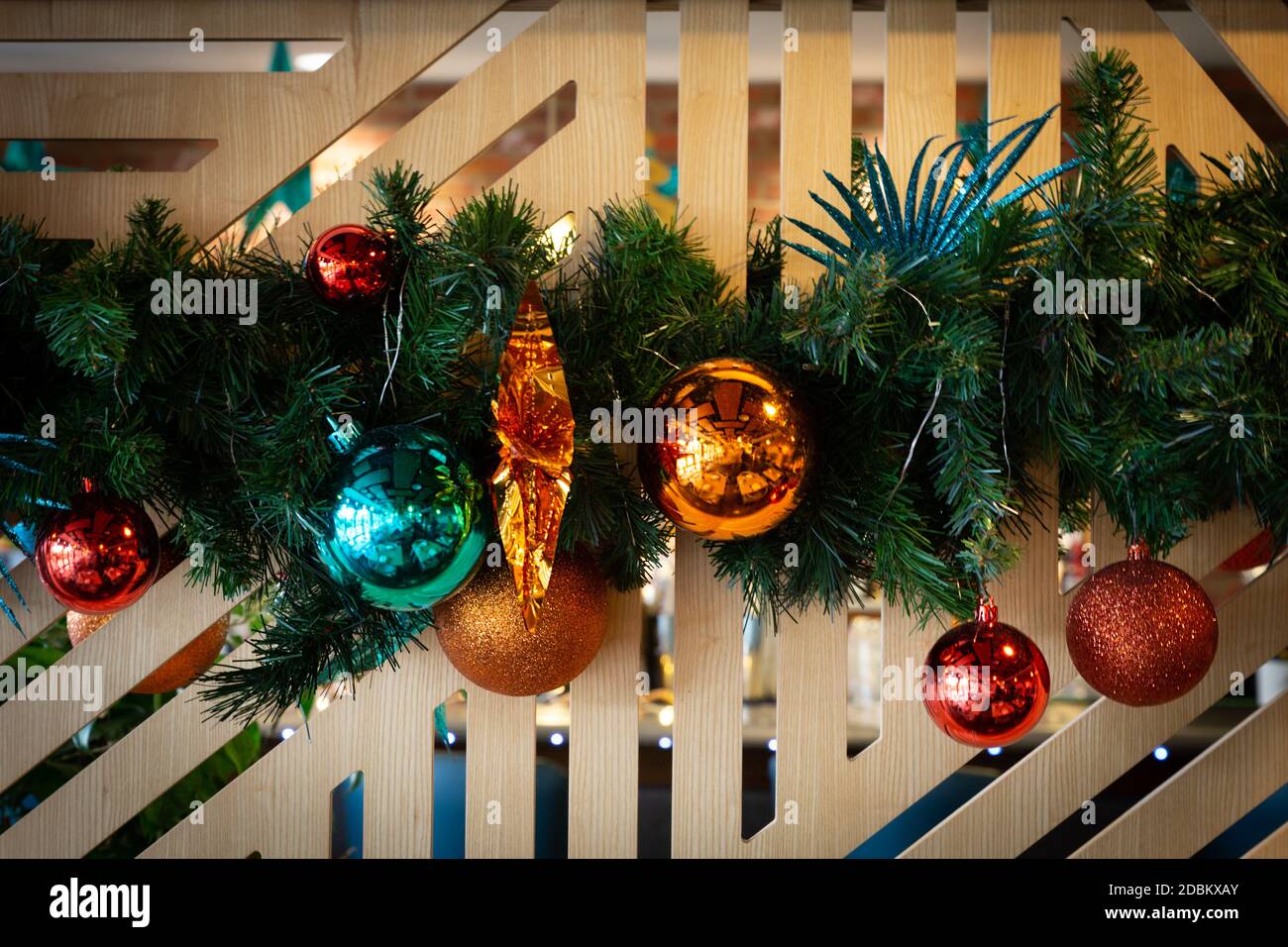 I colorati baubles natalizi e la corona pendono su un elegante schermo in legno. Foto Stock