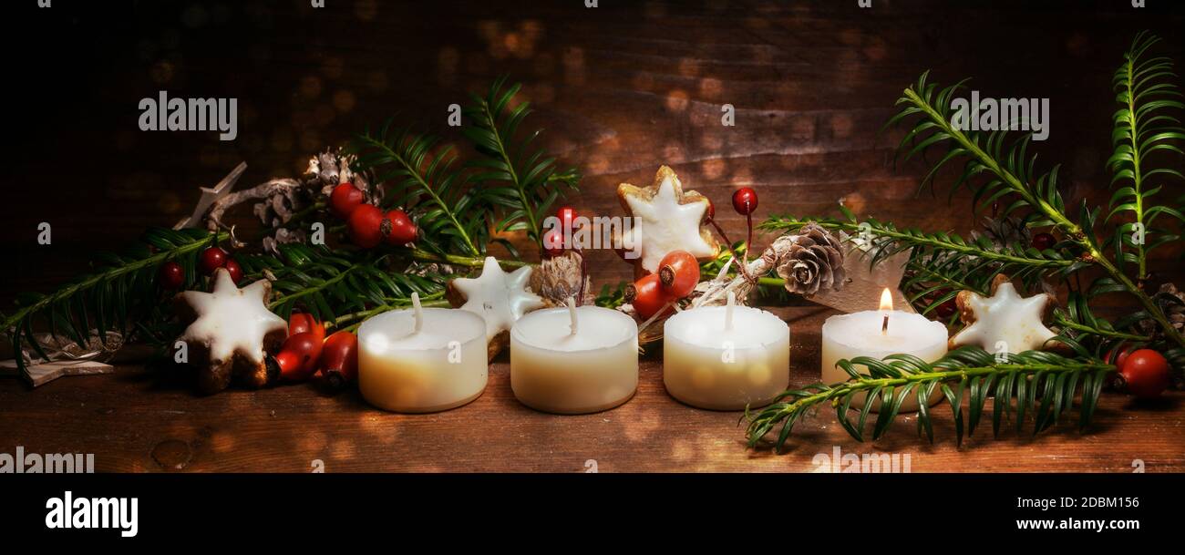 Una piccola candela illuminata per il primo Avvento con decorazione natalizia su legno rustico scuro, formato panoramico, spazio copia, fuoco selezionato Foto Stock