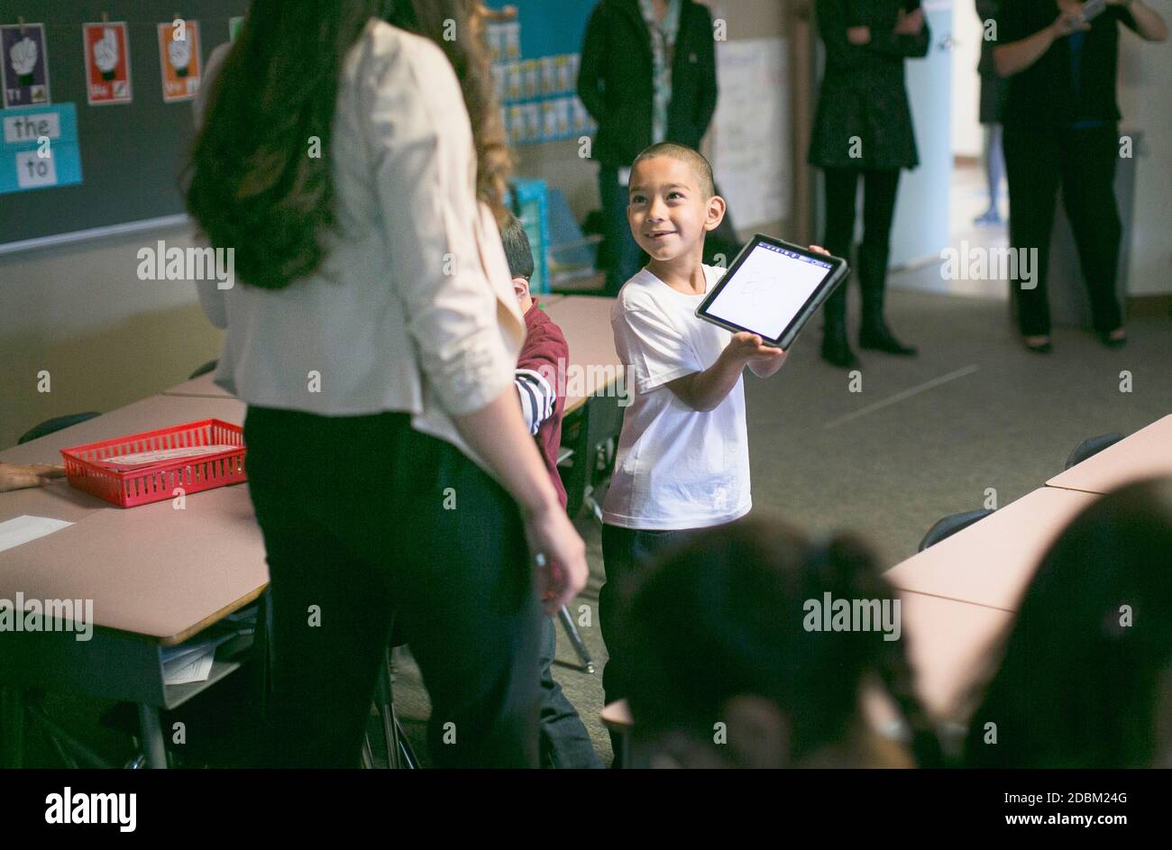 Un ragazzino intelligente mostra le sue lezioni al suo insegnante sul tablet Foto Stock