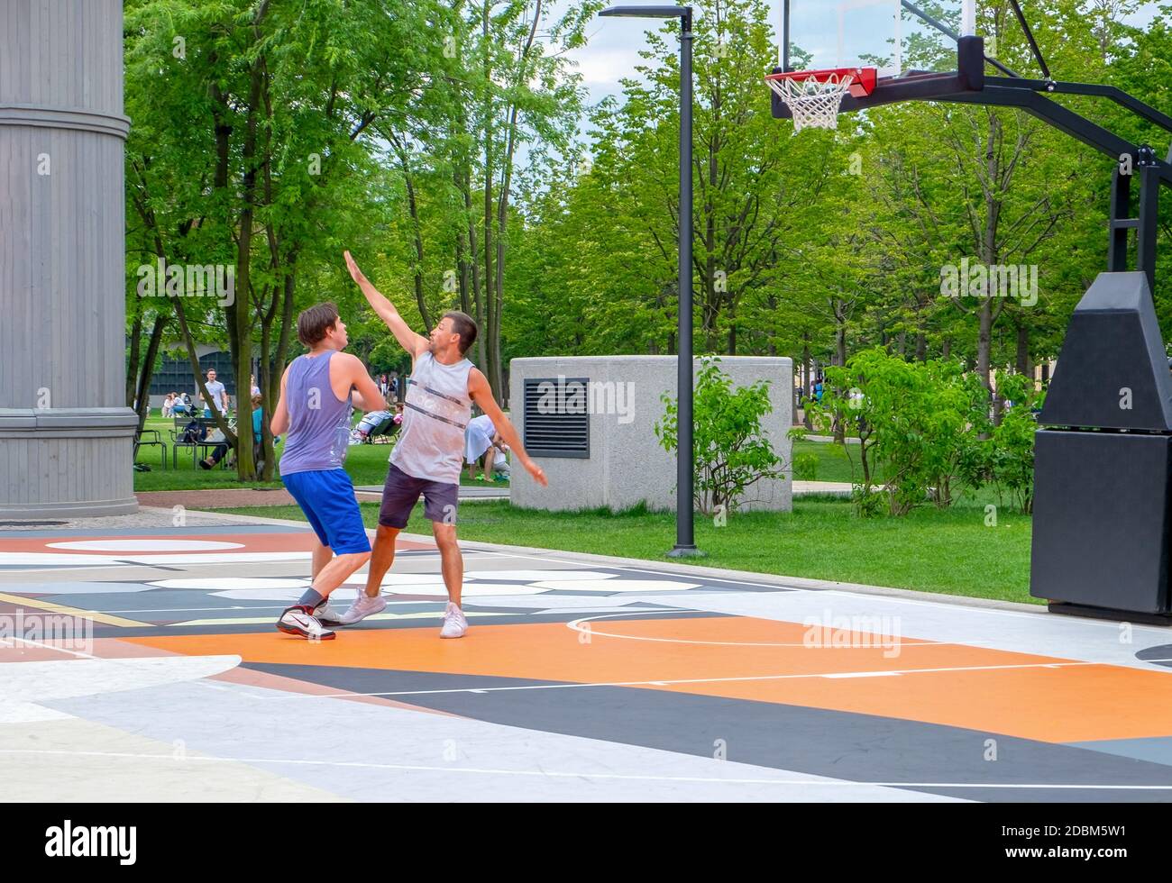 San Pietroburgo, Russia. 28 luglio 2020. Due giovani uomini adulti giocano a basket su un campo da streetball in un parco cittadino. Stile di vita sano, tempo libero attivo. Foto Stock