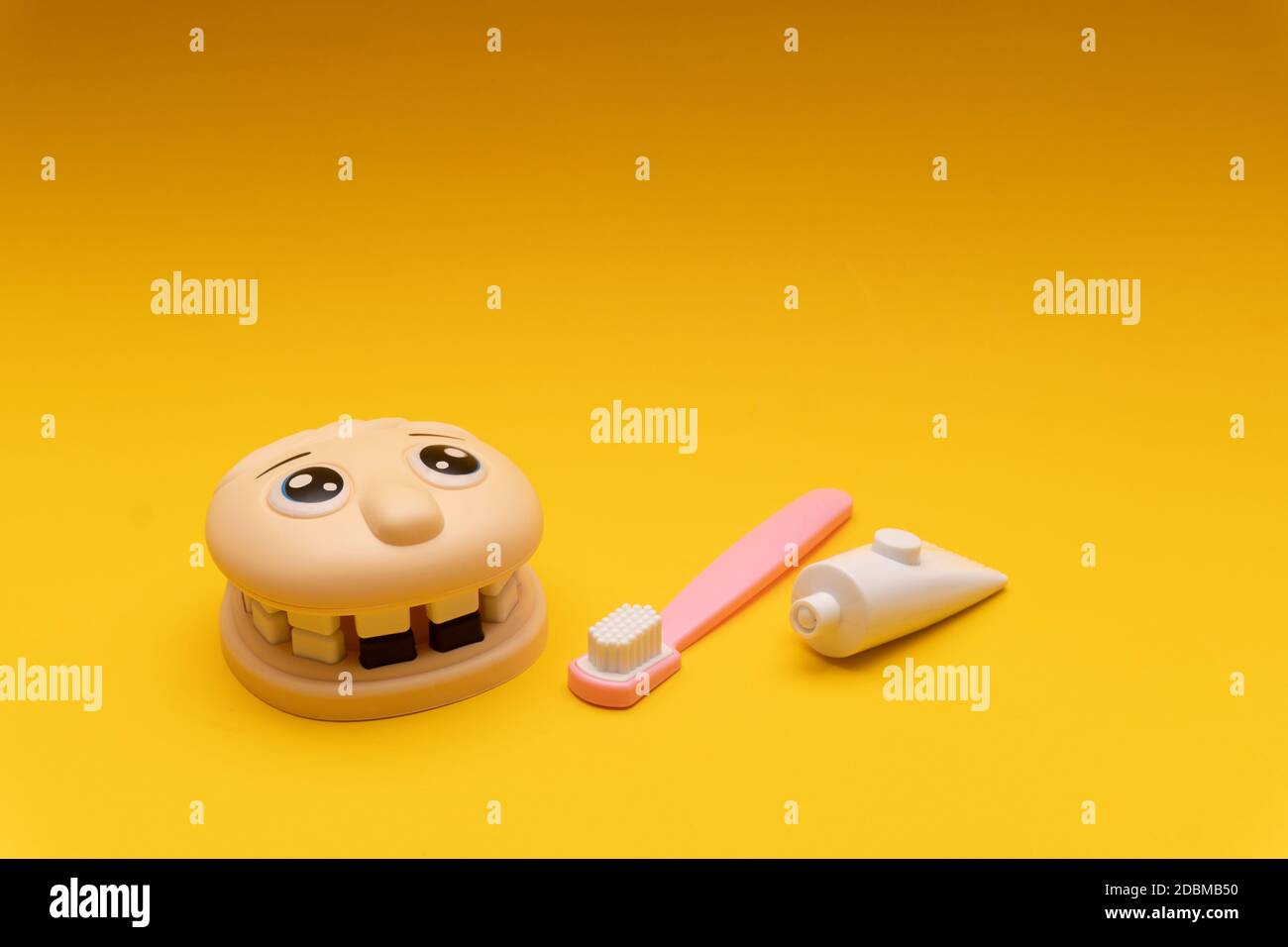 Giocattolo dentale per bambini, mascelle, denti, spazzolino da denti, dentifricio, sfondo giallo Foto Stock
