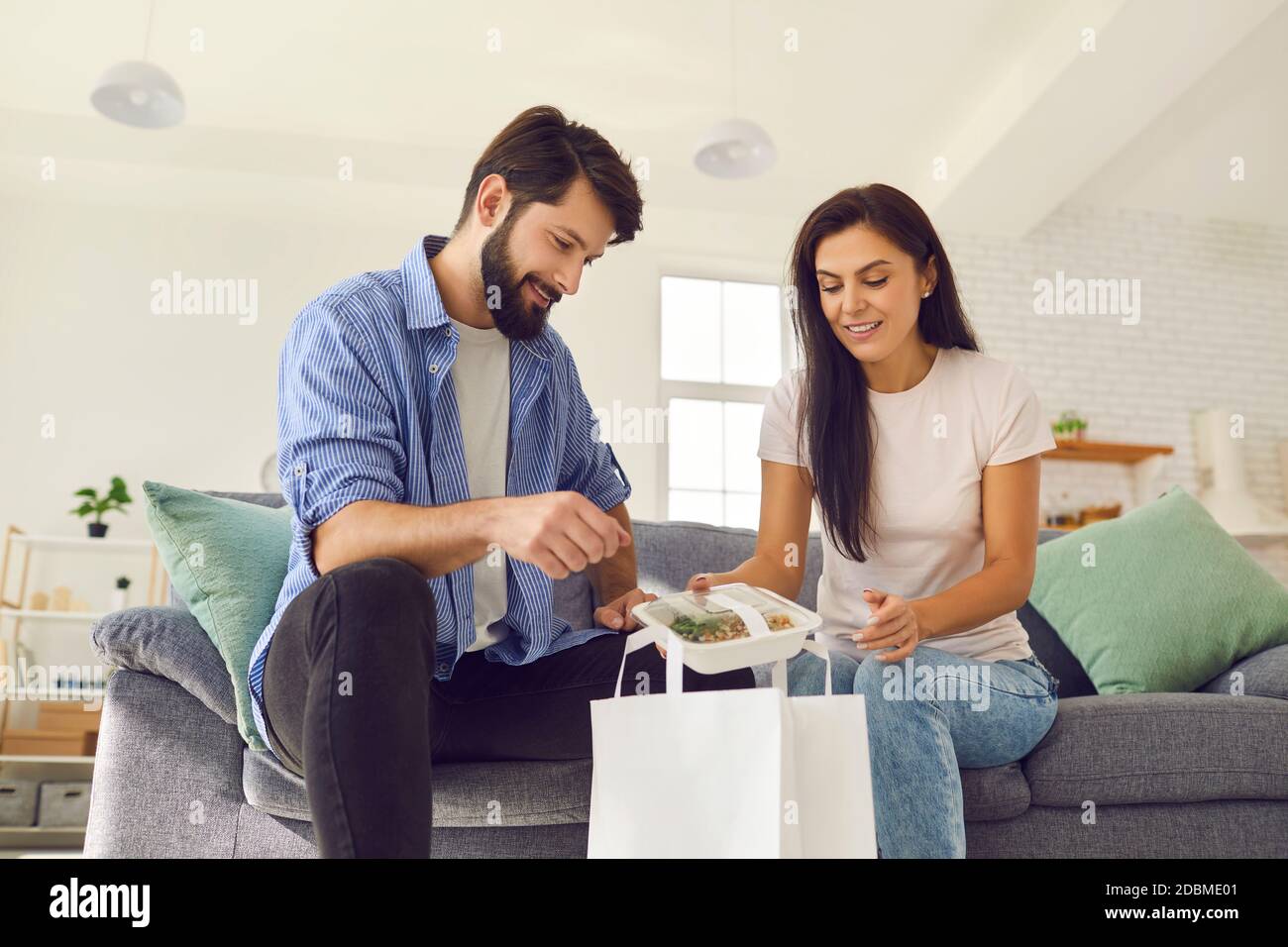 Giovane coppia sorridente disimballare online sano cibo in scatola ordine per consegna della cena Foto Stock