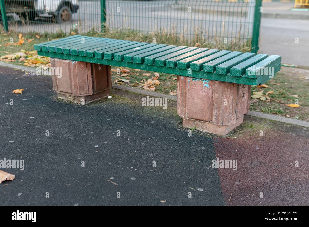 Panca di legno verde sul rivestimento di gomma del parco giochi Foto Stock