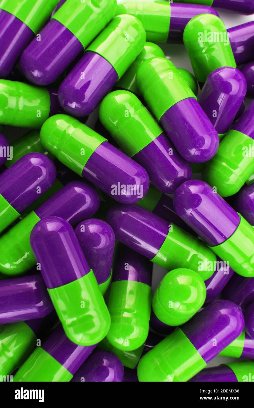 Un mucchio di pillole capsuali verdi e viola Foto Stock