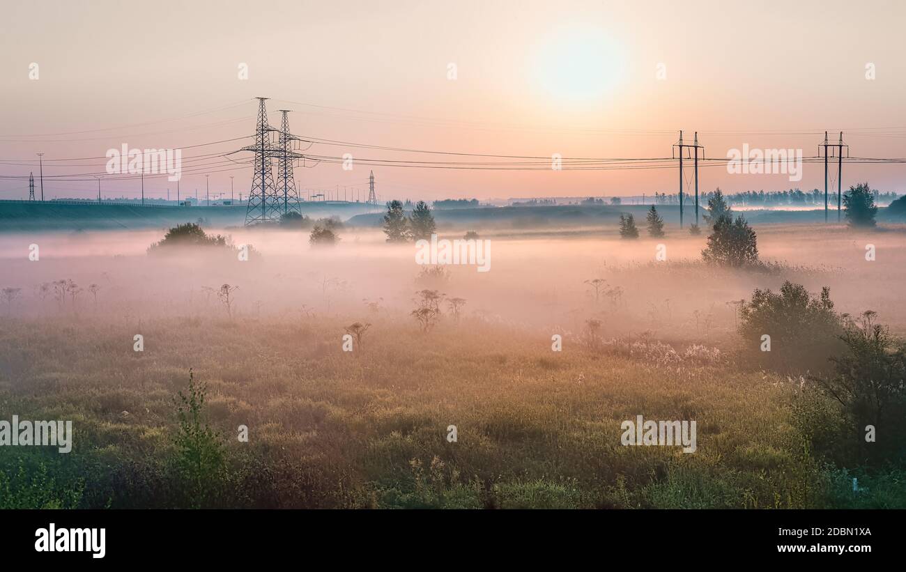 Paesaggio industriale all'alba foggy. Autostrada e linea elettrica nella nebbia mattutina Foto Stock