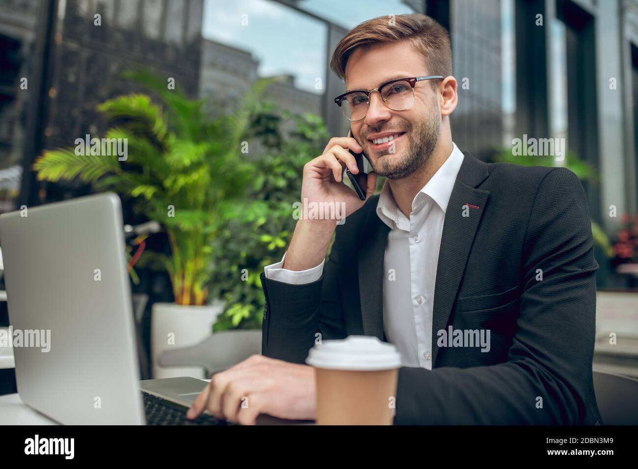 Bel giovane uomo d'affari che parla al telefono e sorridente Foto Stock
