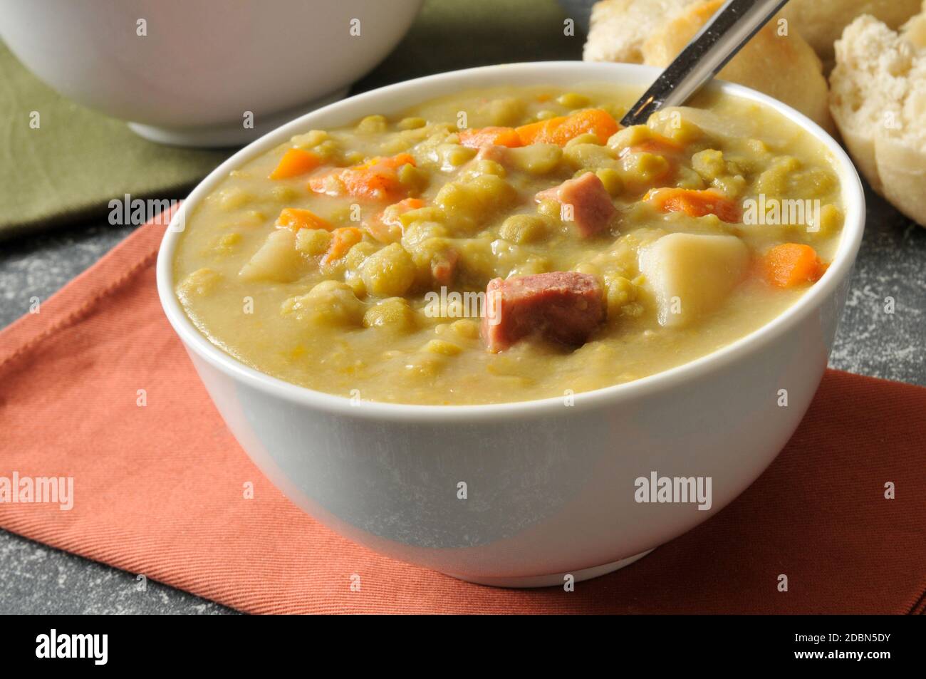 Zuppa di piselli con pezzi di prosciutto e una cena rotolo Foto Stock