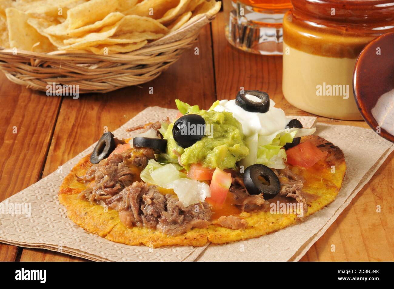 Tostadas di manzo e fagioli con formaggio cheddar, olive nere, panna acida e guacamole Foto Stock