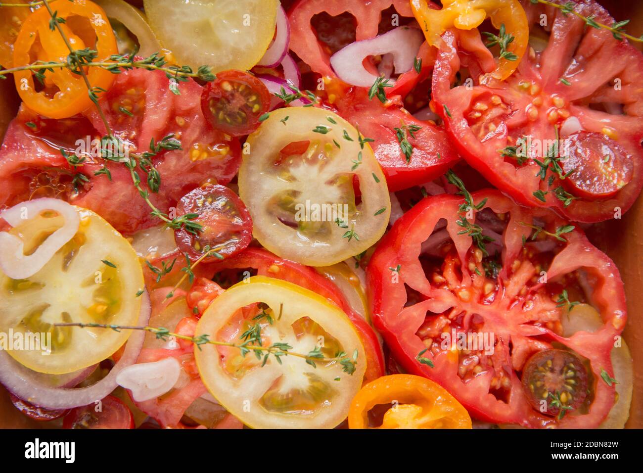 Una selezione di pomodori di cimini a fette che sono stati serviti con un condimento di aceto di vino bianco e olio d'oliva, cipolla rossa a fette e timo fresco. Motore Foto Stock