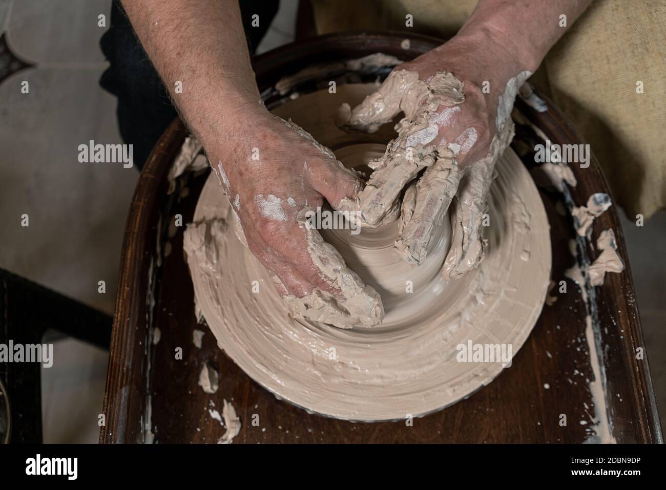 Primo piano di una mano di Potter scolpisce un caraffa di creta su una ruota di Potter Foto Stock