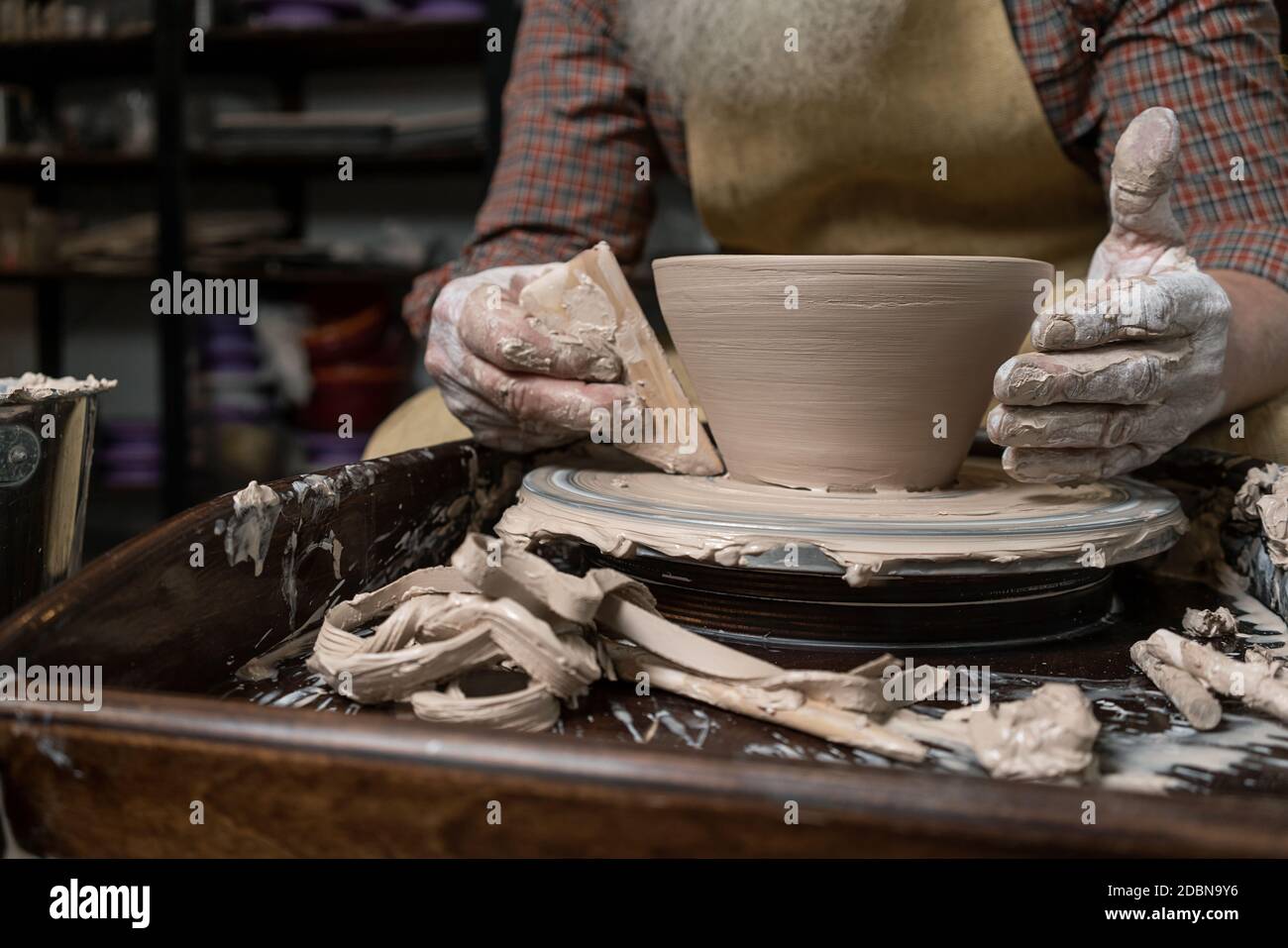 Primo piano di una mano di Potter scolpisce un caraffa di creta su una ruota di Potter Foto Stock