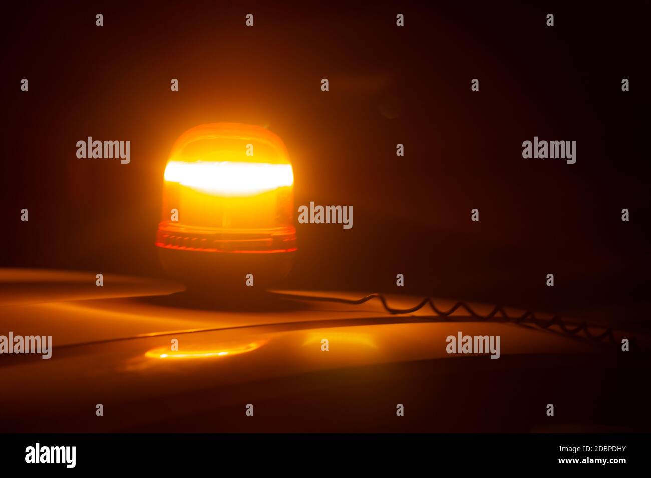 Primo piano di una spia stroboscopica color ambra sul tetto di un'auto di notte. Concetto di emergenza Foto Stock
