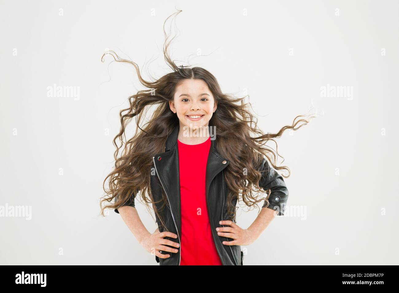 Aggiunta di cura per i capelli. Adorabili piccole bambine sorridenti con lunghi mossi brunette capelli su sfondo giallo. Pazienti pediatrici health care. Adottare un bambino e dare una cura. Foto Stock