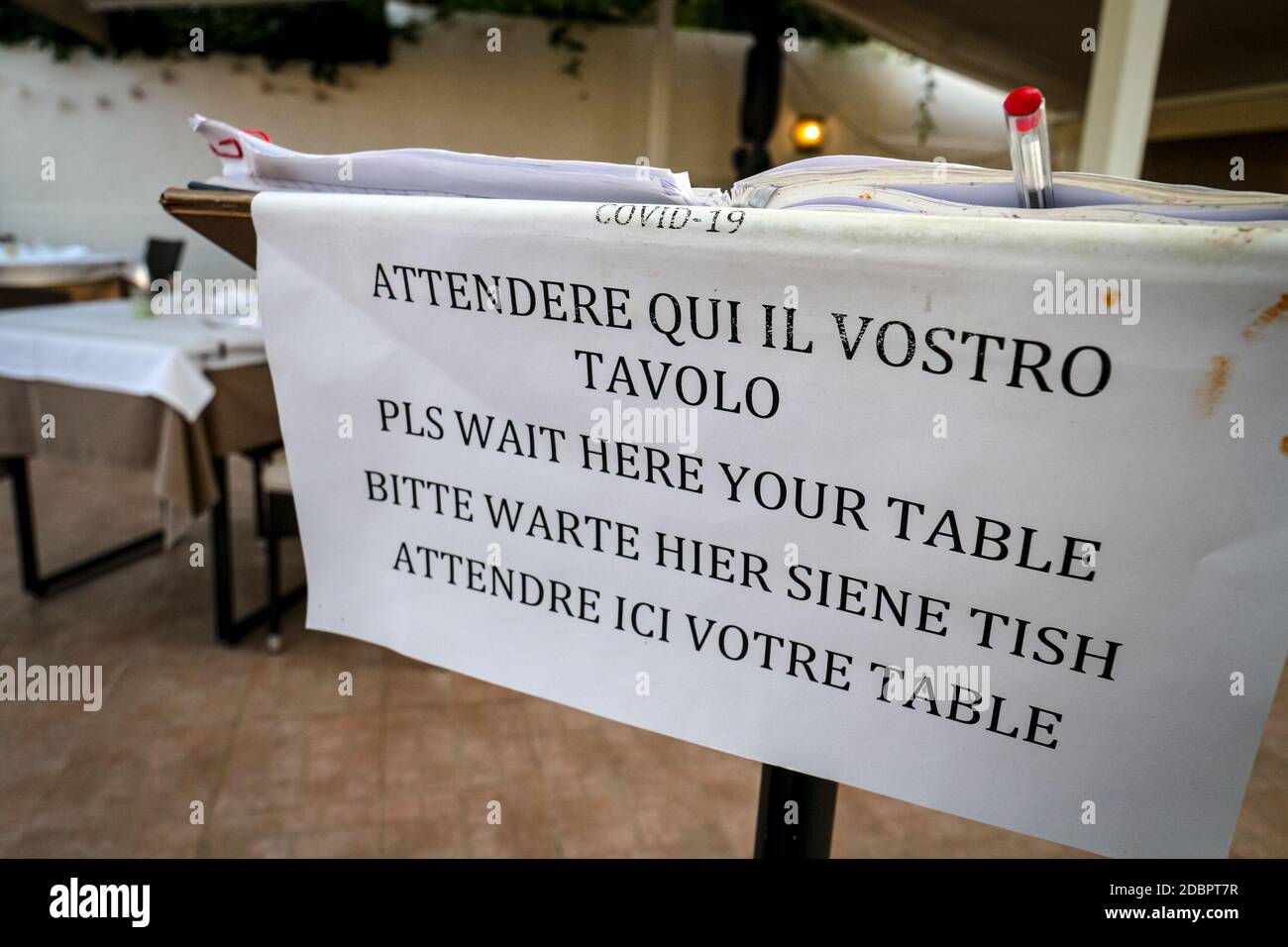Il cartello del ristorante informa gli ospiti di aspettare fino a sedersi in diverse lingue, assicurando le normative di distanza sociale durante la pandemia del coronavirus. Foto Stock