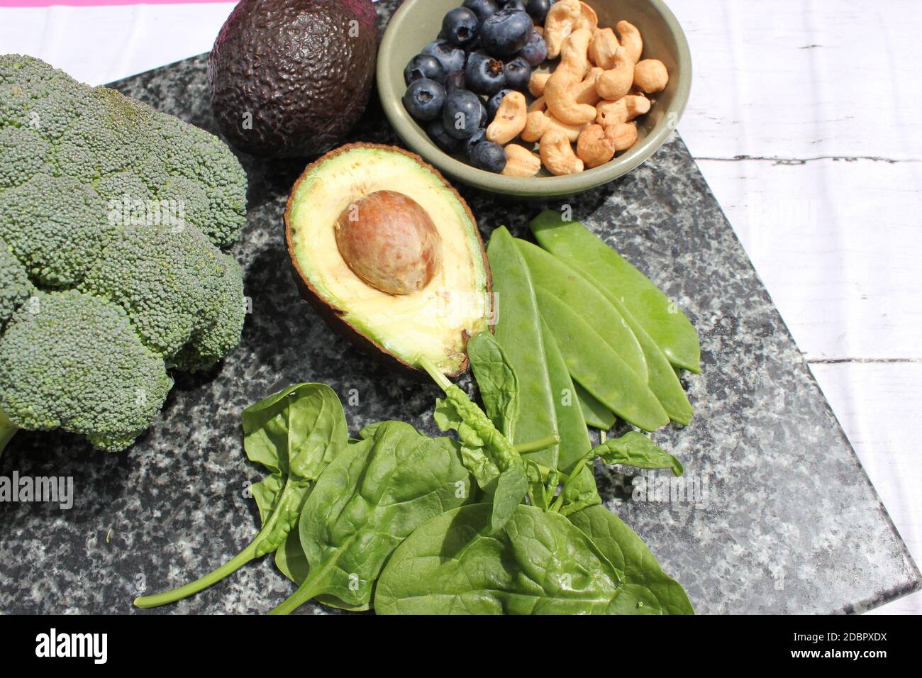 Dieta vegetariana vegana a base di piante selezione senza glutine di noci di anacardi, mirtilli, spinaci, piselli da mange e tois avocado e broccoli su sfondo di marmo e tavola Foto Stock