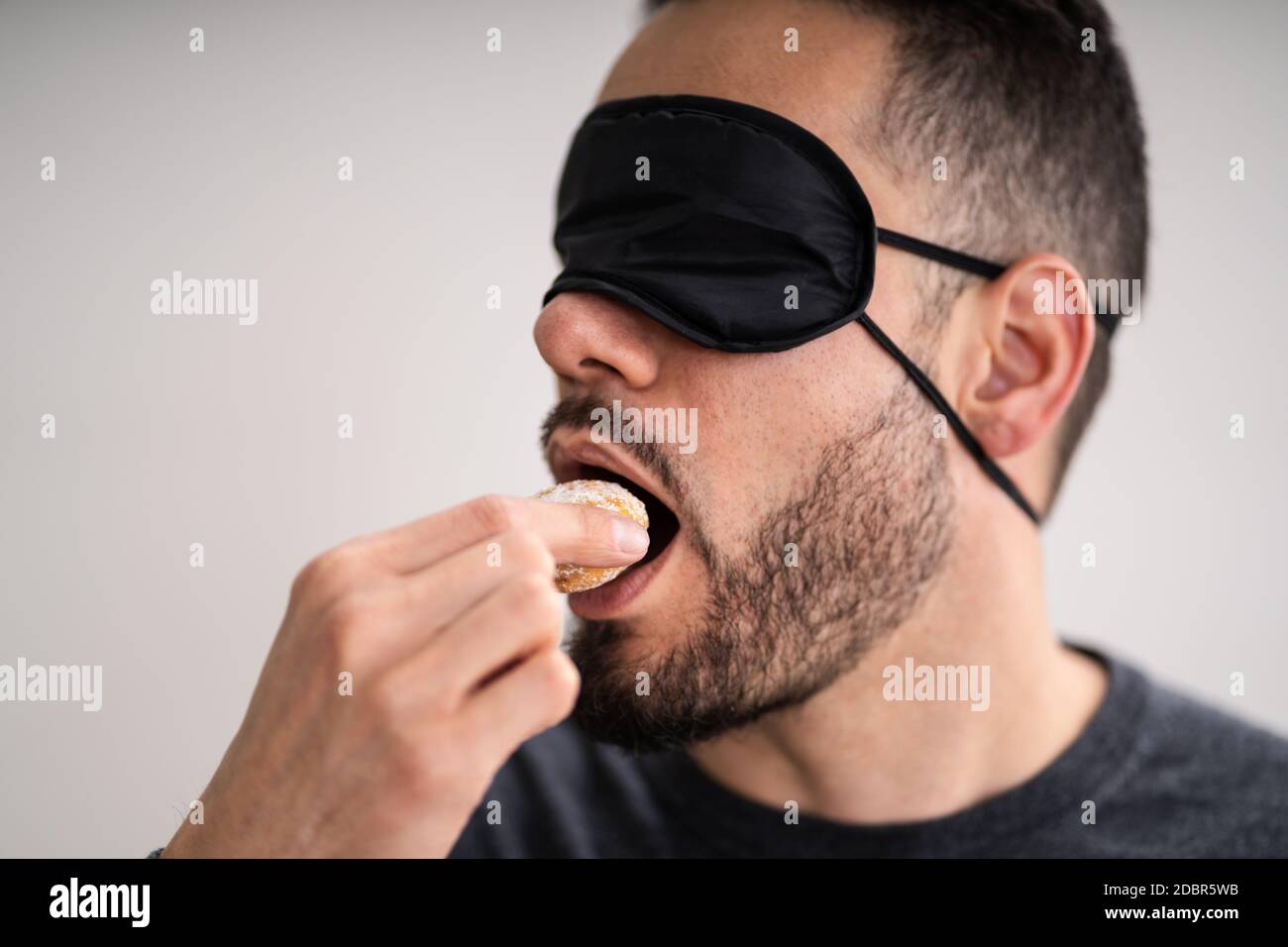 Gusto cieco. Test alimenti bendati. Uomo faccia Foto Stock