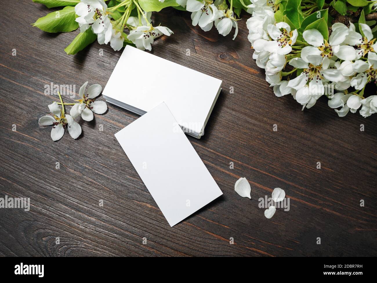Foto di biglietti da visita e fiori bianchi su sfondo di legno. Modello per ID. Foto Stock