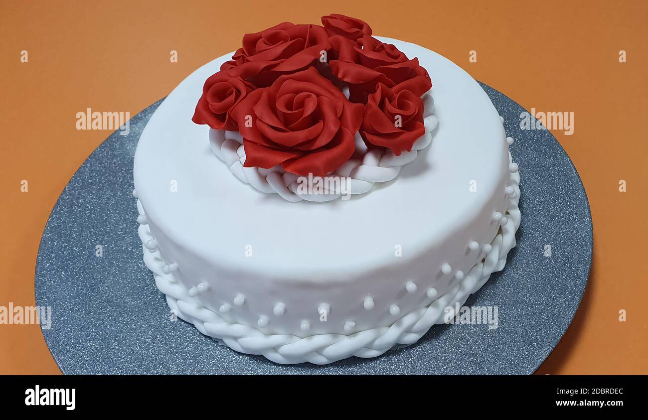 La torta è ricoperta di pasta di zucchero bianca e decorata con rose rosse  Foto stock - Alamy
