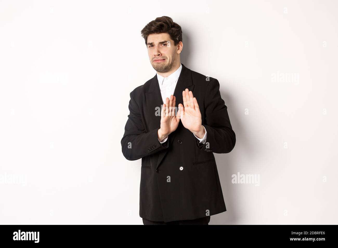 Immagine di elegante bell'uomo in tuta nera, frangia da qualcosa di  imbarazzante, declino offerta e mostrando stop gesto, in piedi contro  bianco Foto stock - Alamy
