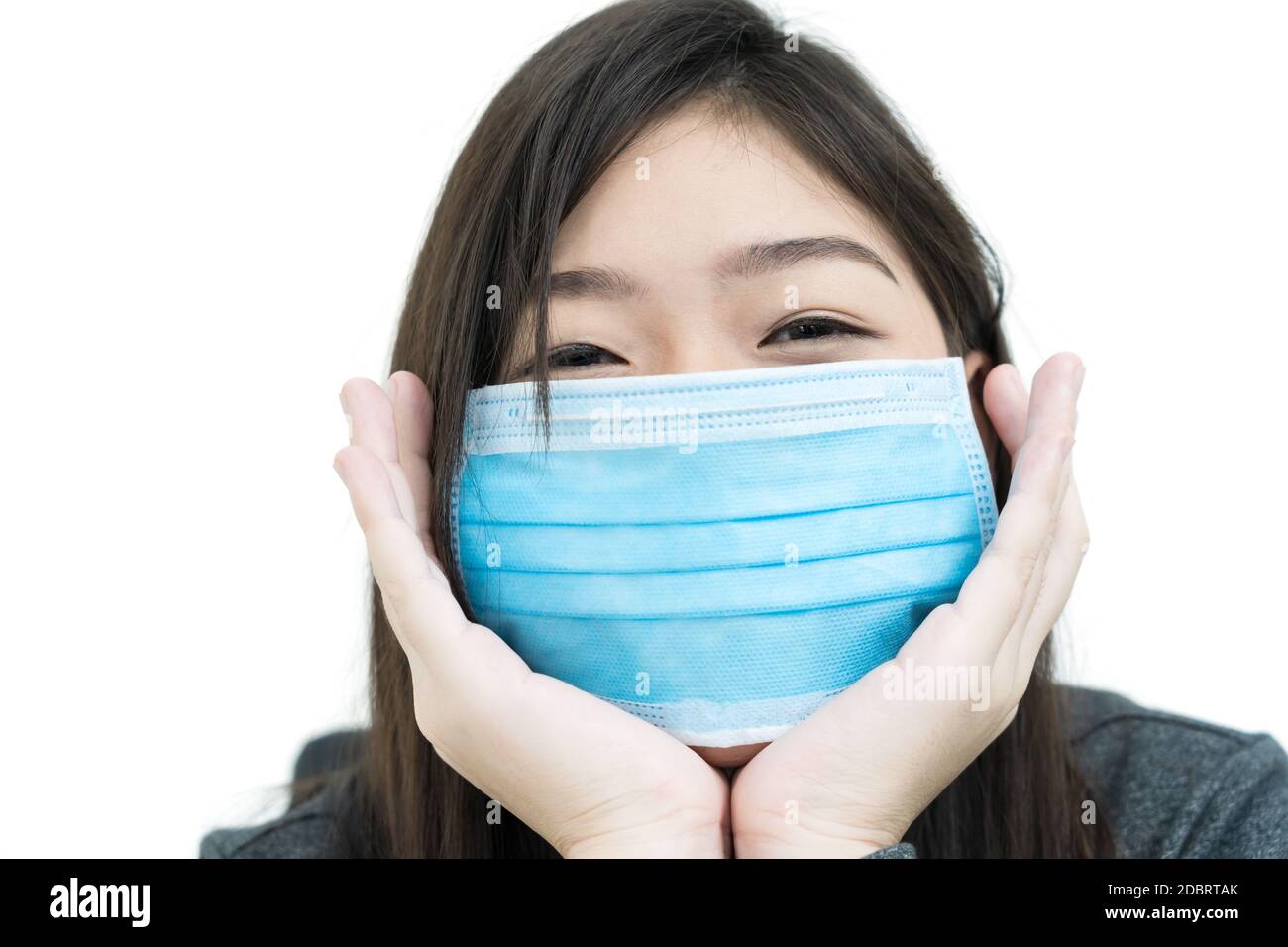 Primo piano donna capelli lunghi che puntano sul mento con il suo Mani e indossare maschera protettiva per la protezione contro il virus Covid-19 su bianco Foto Stock