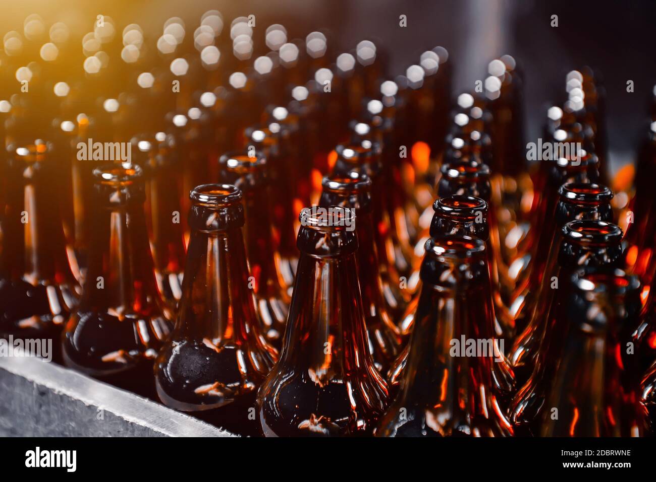 Bottiglie di birra in vetro di colore marrone sulla linea di trasporto di imbottigliamento della birra da vicino Foto Stock