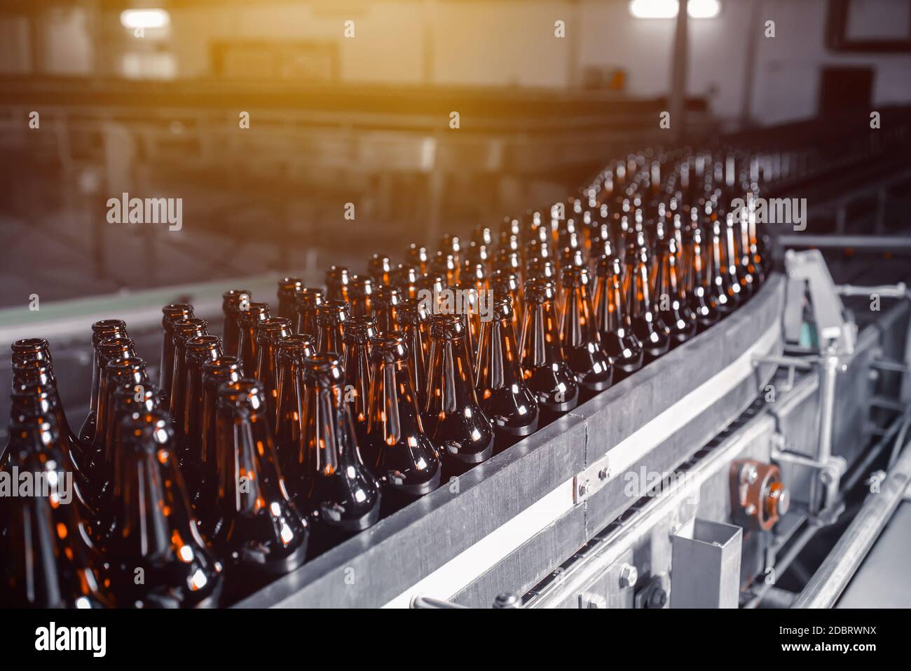 Bottiglie di birra in vetro di colore marrone sulla linea di trasporto di imbottigliamento della birra da vicino Foto Stock