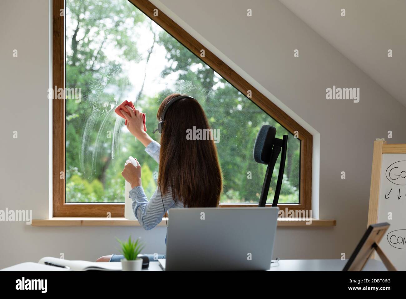 Donne lavano le finestre mentre su una chiamata di conferenza al lavoro. Nuovo concetto normale. Foto Stock