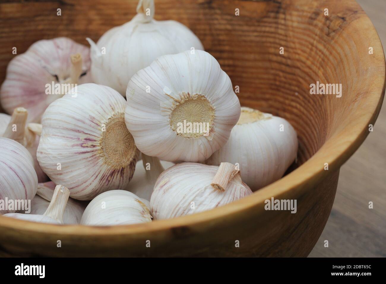 Spicchi d'aglio e bulbo in una ciotola di legno d'epoca. Foto Stock