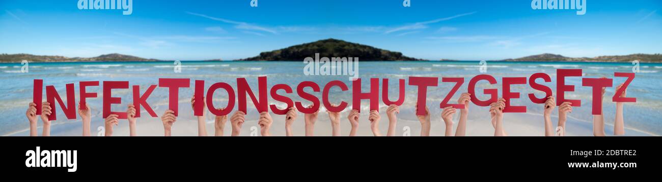 Persone mani Holding Red parola tedesca Infektionsschutzgesetz significa legge sulle infezioni. Oceano e Spiaggia come sfondo Foto Stock