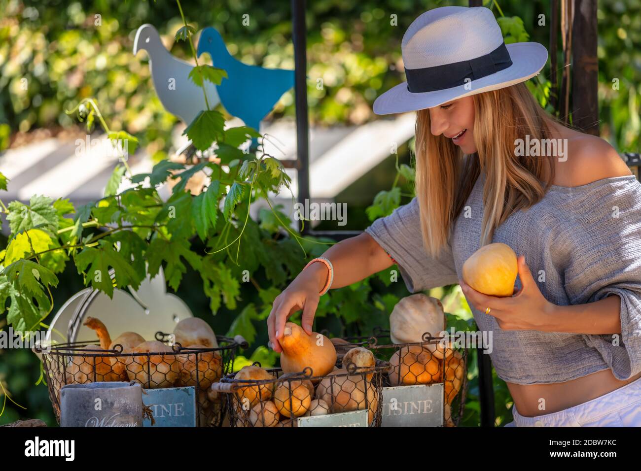 Bella giovane femmina al mercato di verdure all'aperto. Con piacere scegliere Mini Pumpkins freschi maturi. Nutrizione organica. Stile di vita sano. Foto Stock