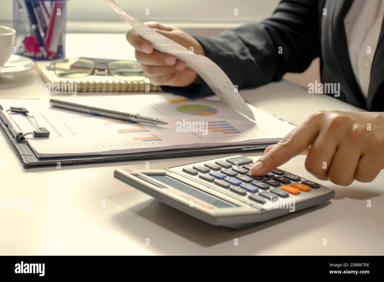 Le donne di affari che stanno usando le loro dita per premere il calcolatore per calcolare le fatture nell'ufficio. Foto Stock